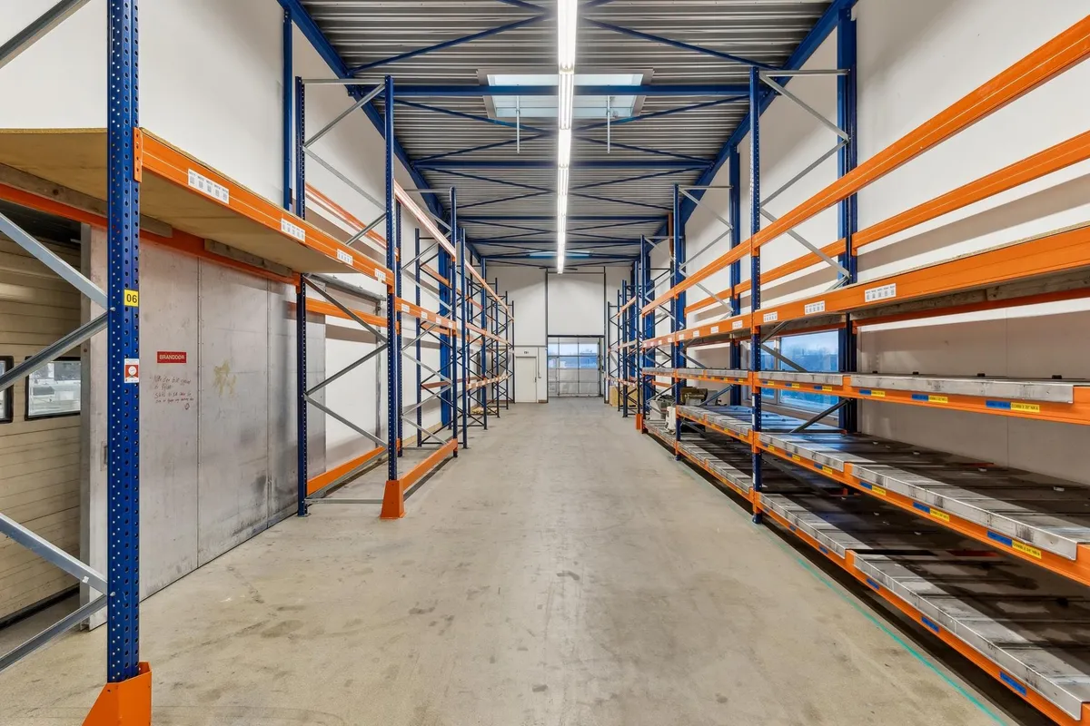 Lager med gulvmonterede lagerreoler og gulvmonterede paletter samt glasdøre og et skyloft med lysepaneler