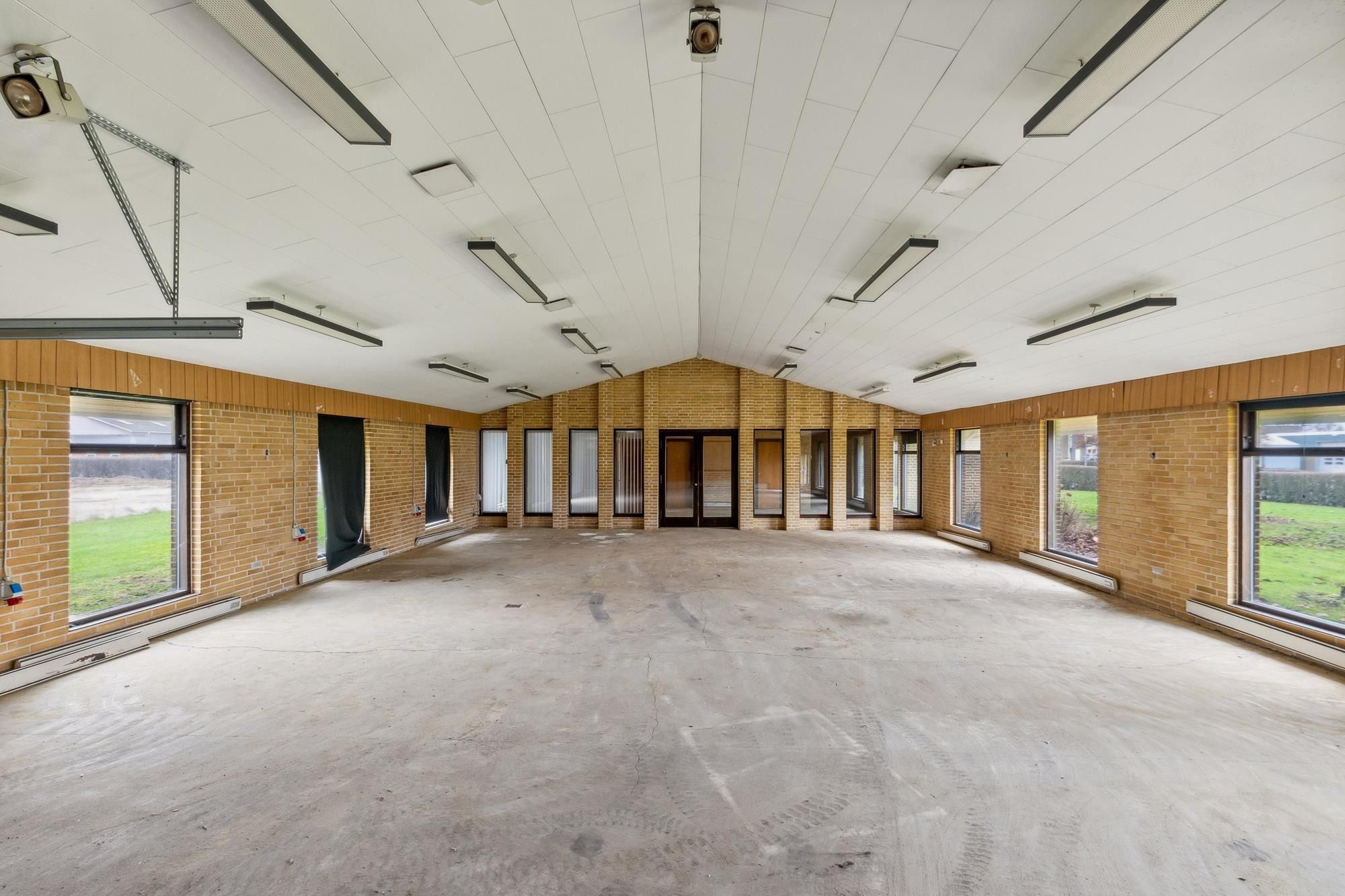 Lyse lofter, hvide vægge, lysegrå gulv og gule mursten. Dobbeltglasruder, hvide rudegardiner og åbne vinduer.