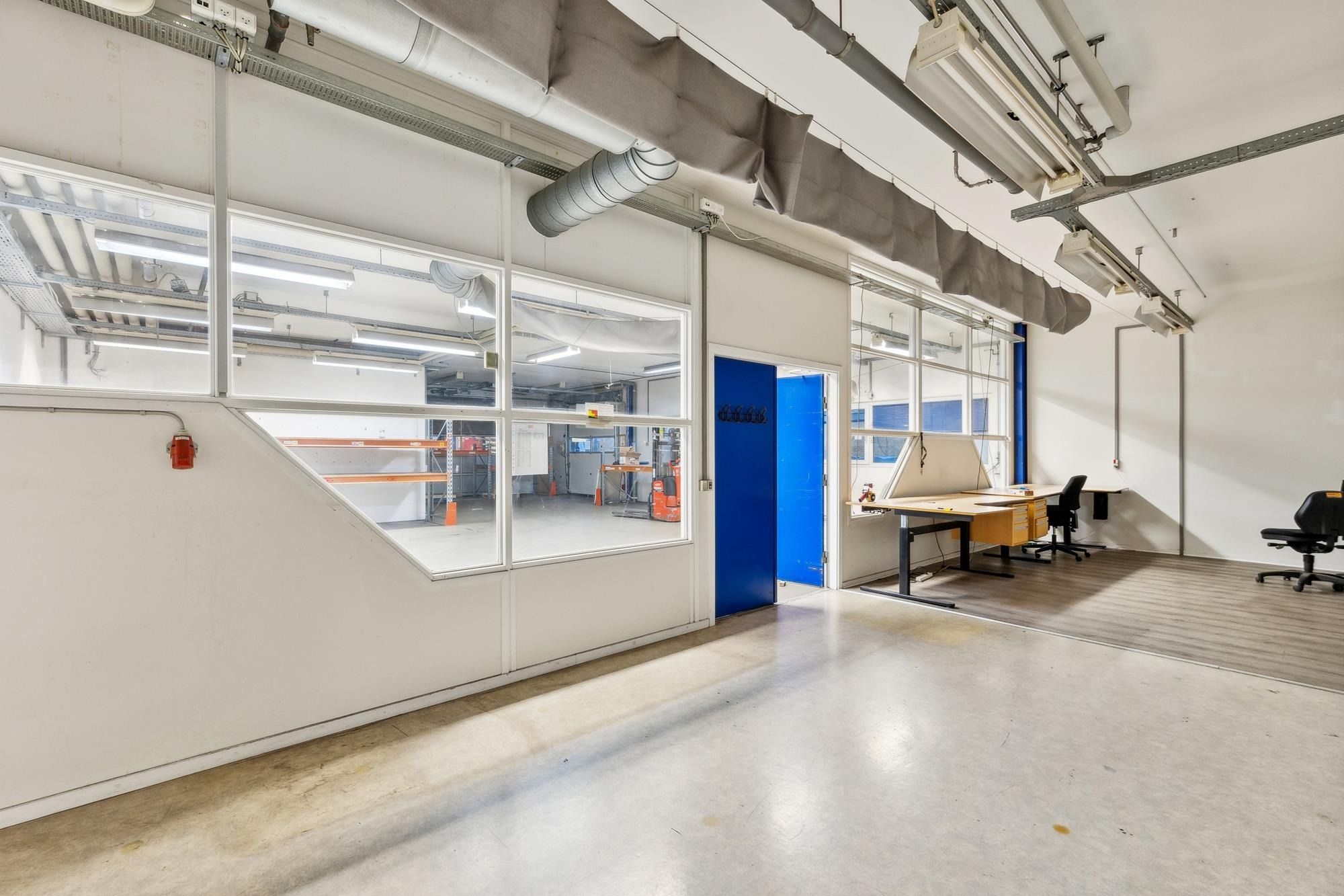 Værksted med glasvinduer og kontor med bord og stole samt højdejusterbar bord, der er let at tage i brug og er funktionel