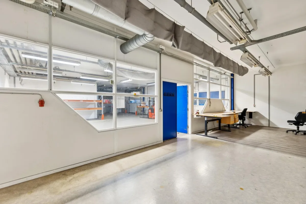 Værksted med glasvinduer og kontor med bord og stole samt højdejusterbar bord, der er let at tage i brug og er funktionel