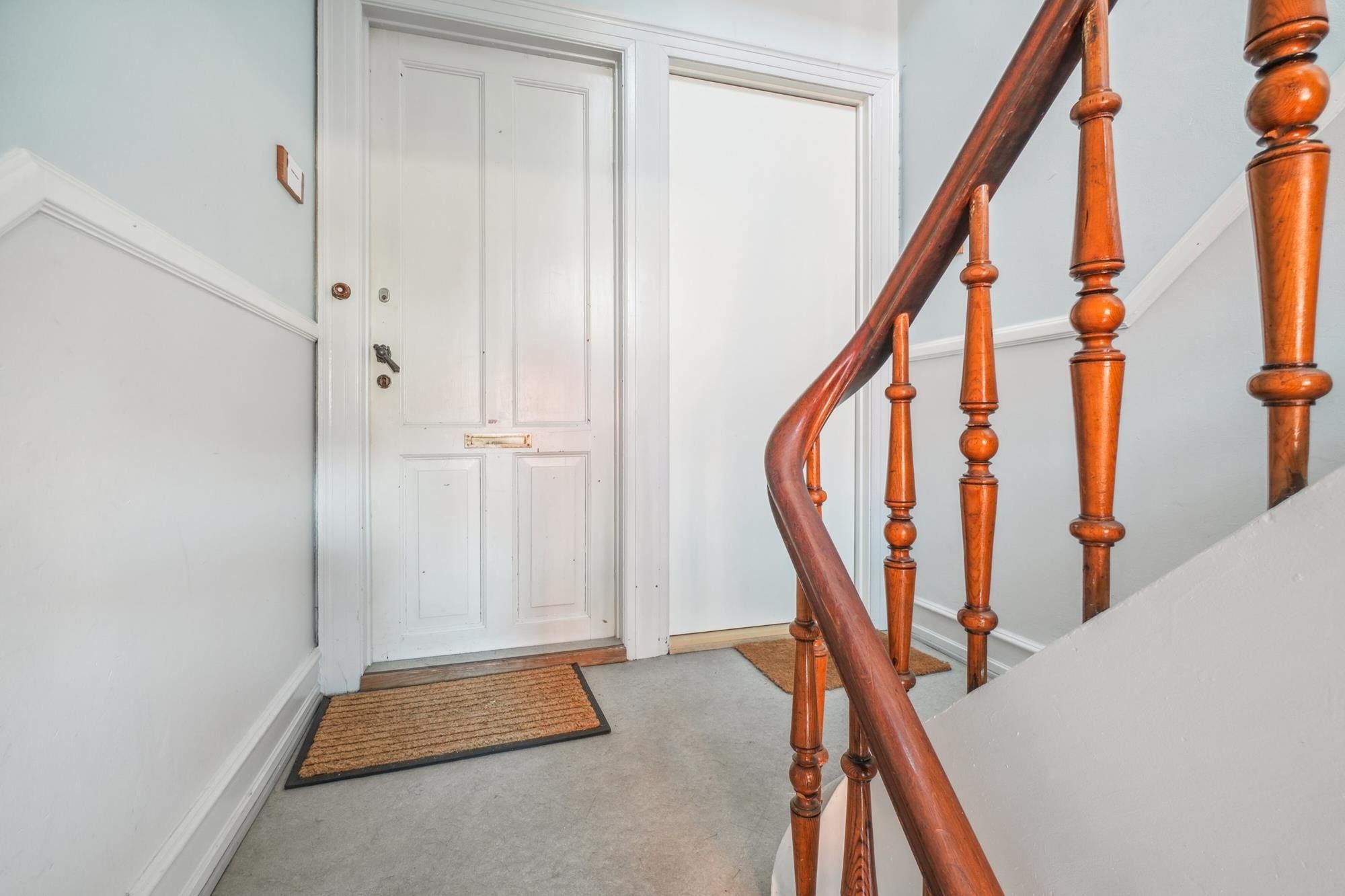 Hvid og glat indgangsdør til et smukt hus med hårdt træ stige og lyse vægge.