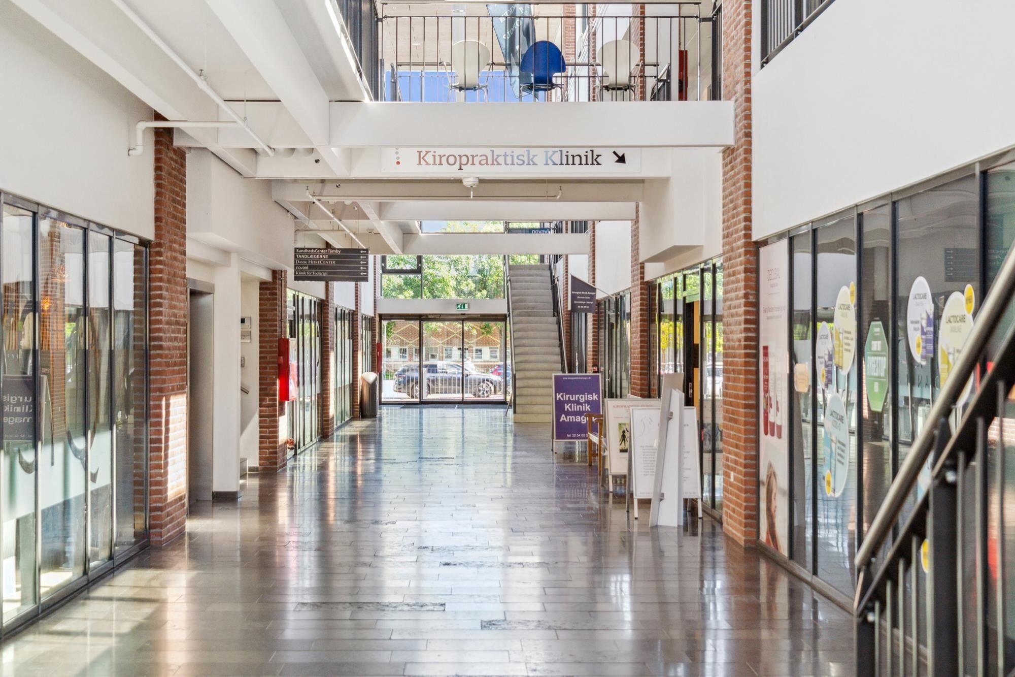 Hallen er møbleret med vægge og gulv i røde mursten og glasvinduer og skilte med tekst og billeder samt trappe