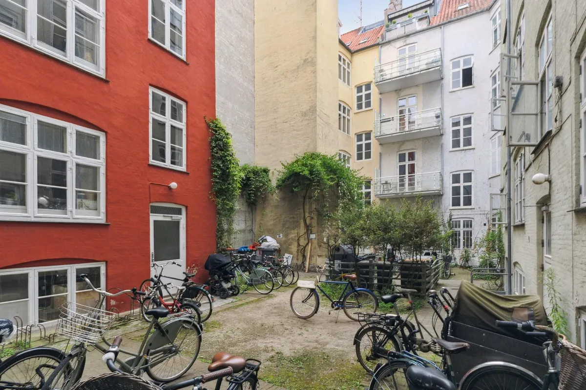 Forskellige farvede bygninger med vinduer og balkoner, tomme gader, og mange parkerede cykler