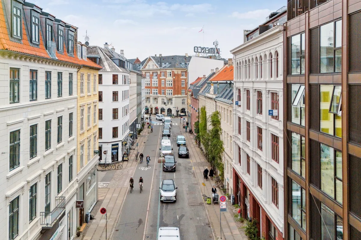 Store Kongensgade i København med biler, cyklister og gående forbi huse med gule og røde tag