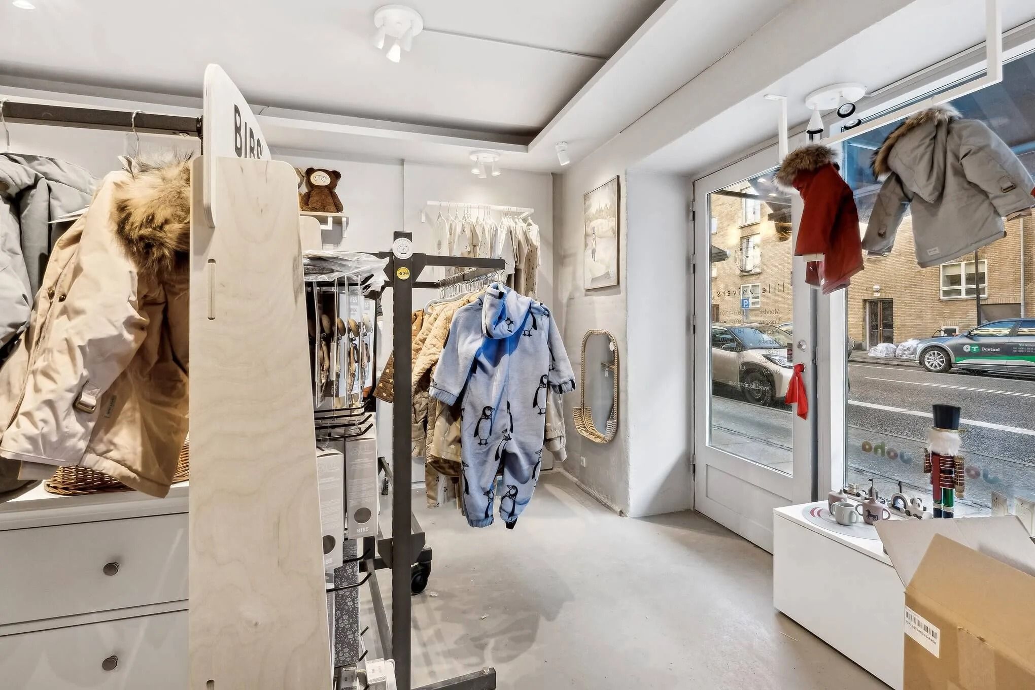 Københavnsbutik med udstilling af tøj og tøjskabe samt dekorative træfigurer og kunstværker på væggen