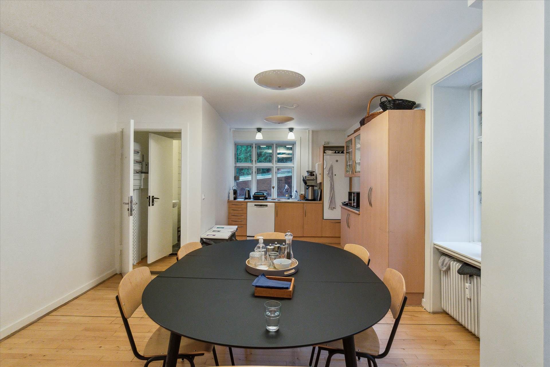 Mødelokalet med køkken, runde bord, to lysekroner og lyse lamper på loftet