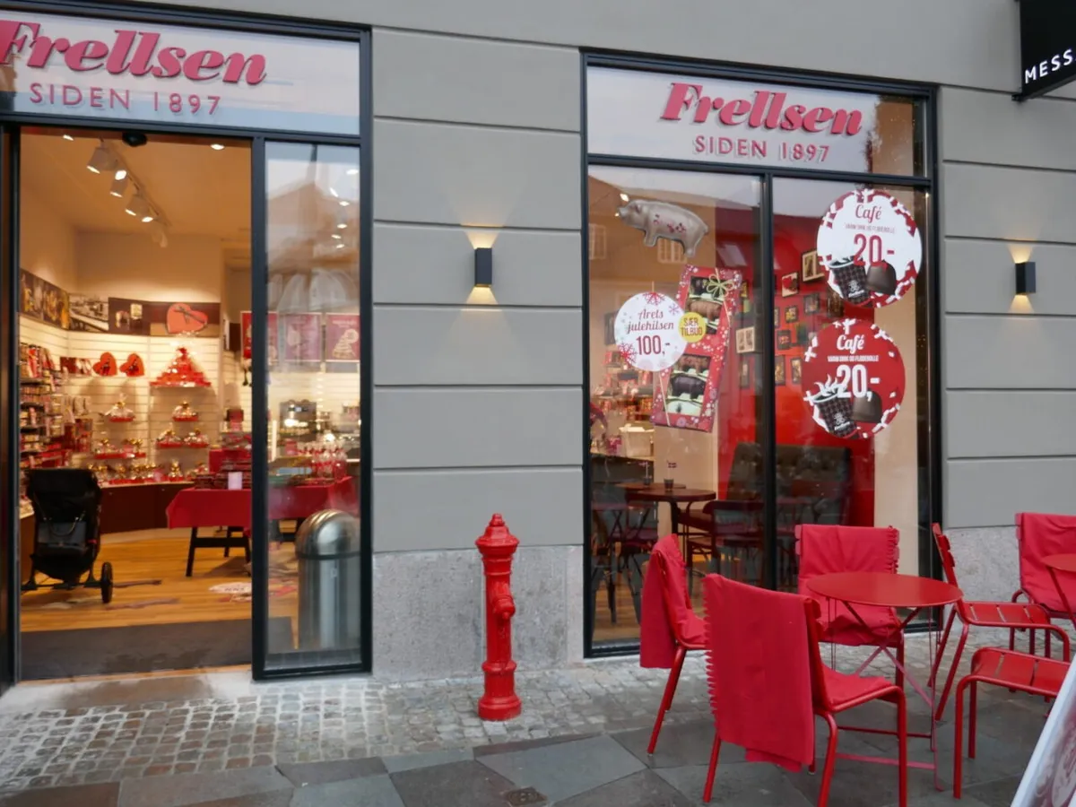 Frellsen café med røde stole og runde borde og et rødt brandhjul foran bygningen