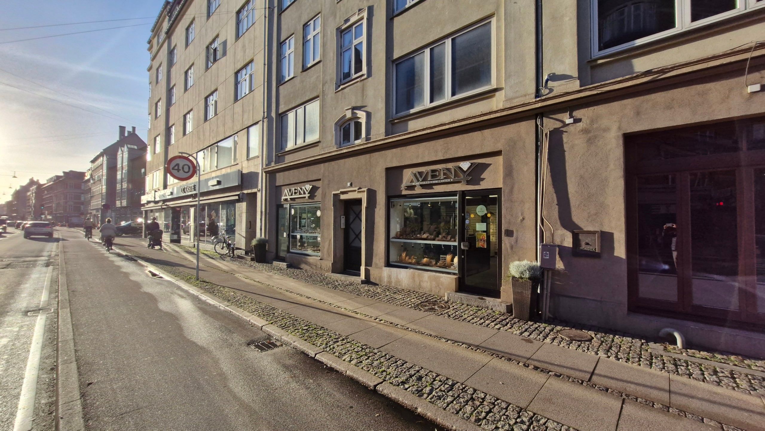 En fredelig gågade med gågadefortov, forretninger, cykelstel og mennesker samt en farverig facade og en