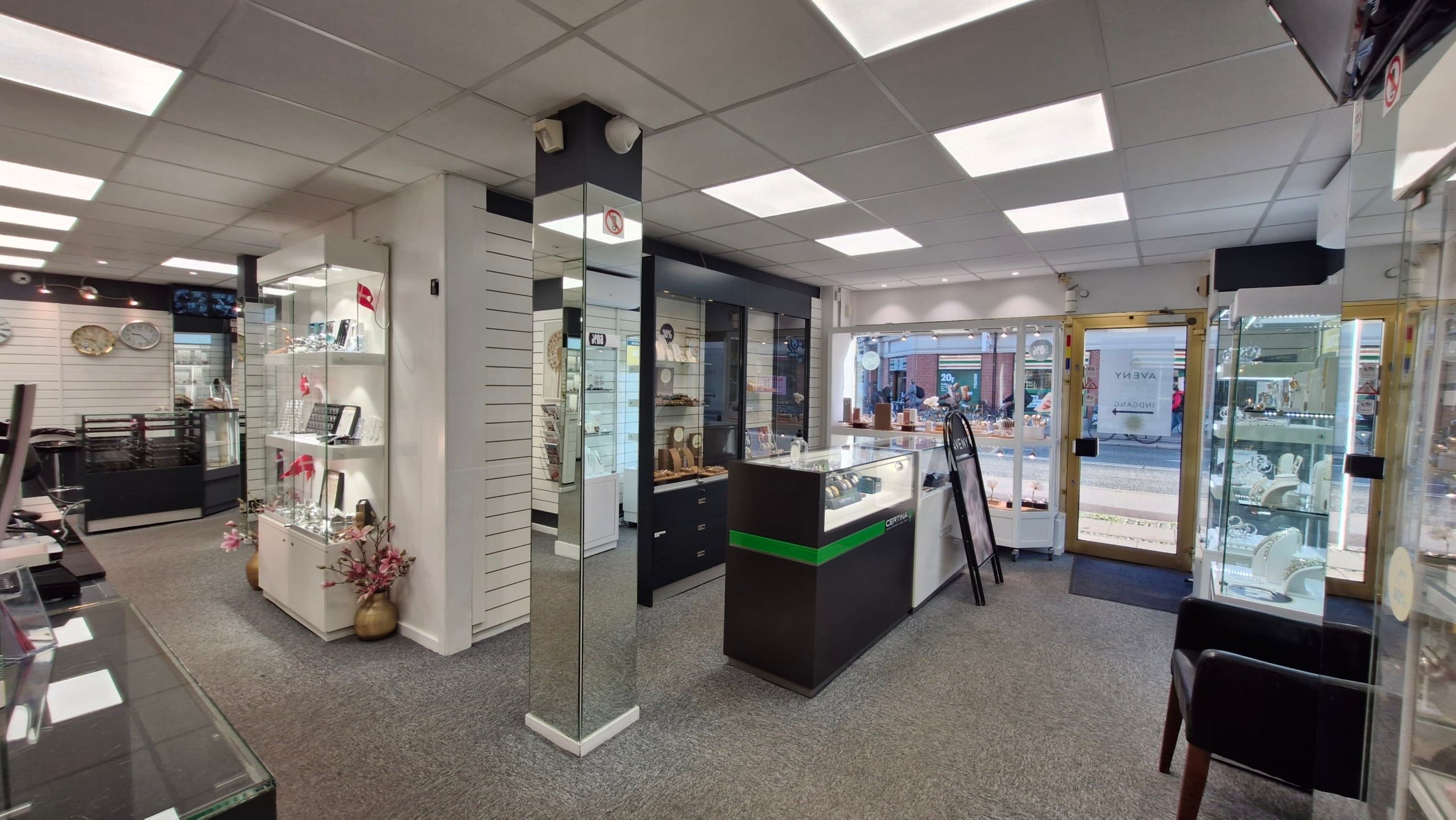 En pæn erhvervsandel med glasvinduer og udskårne søjler, der er indrettet med flere udstille og spejle. Væggene er hvide, og