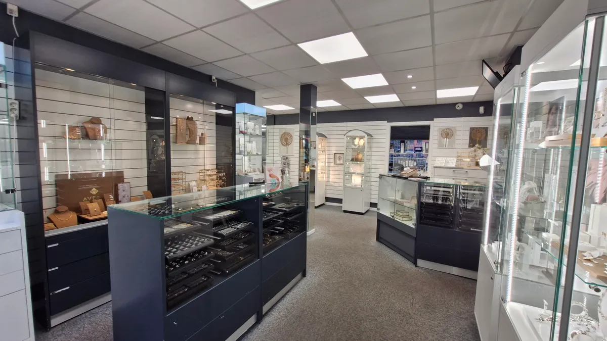 En erhvervsandel med smykkebutik med flere smykkeskuffer og udstillerede smykker i udsagnene samt en mørk gulvbelægning og