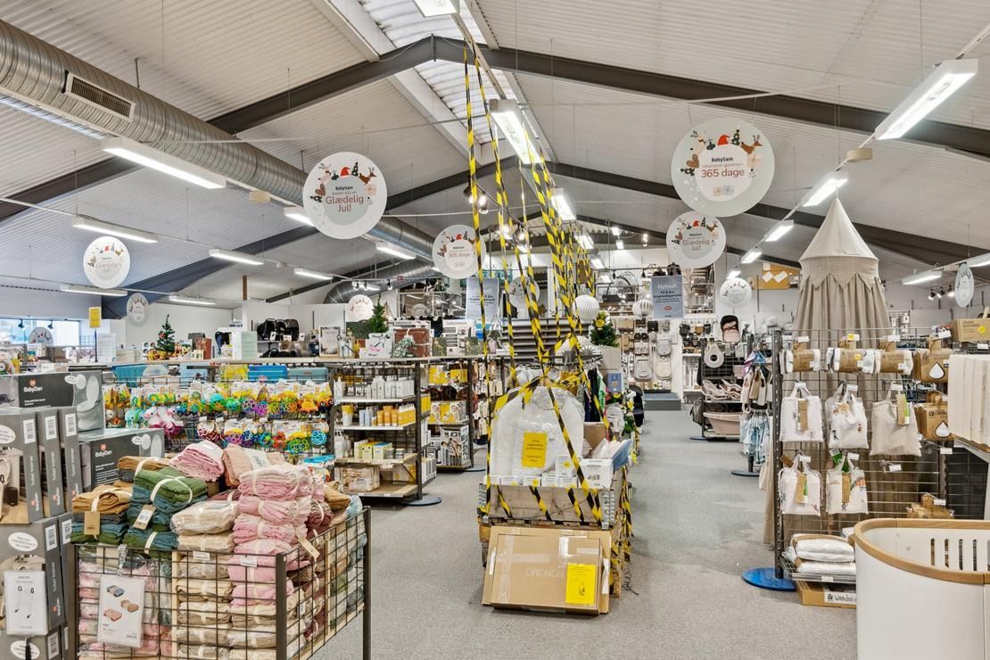 Store indretning med højtloft og lyse lamper. Hylle med forskellige babyprodukter og dekorative smykker. Flertal af