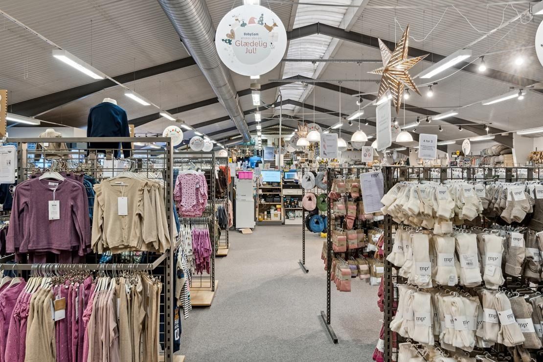 Indvendigt lager med babytøj, klædeskabet med tøj på bøjle og papirhætter med priser.