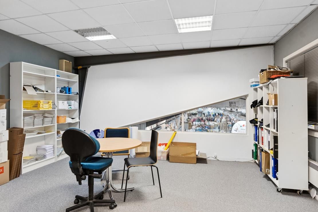 Moderne kontor med højloft, hvide vægge, lysekroner, runde bord, kontormøbler, og høje hylder med skriftlig materiale og