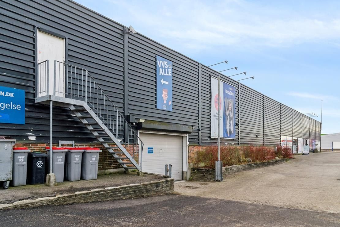 En stor, sort bygning med tre skraldespande og to skilte. VVS er skrift på et af skiltene.