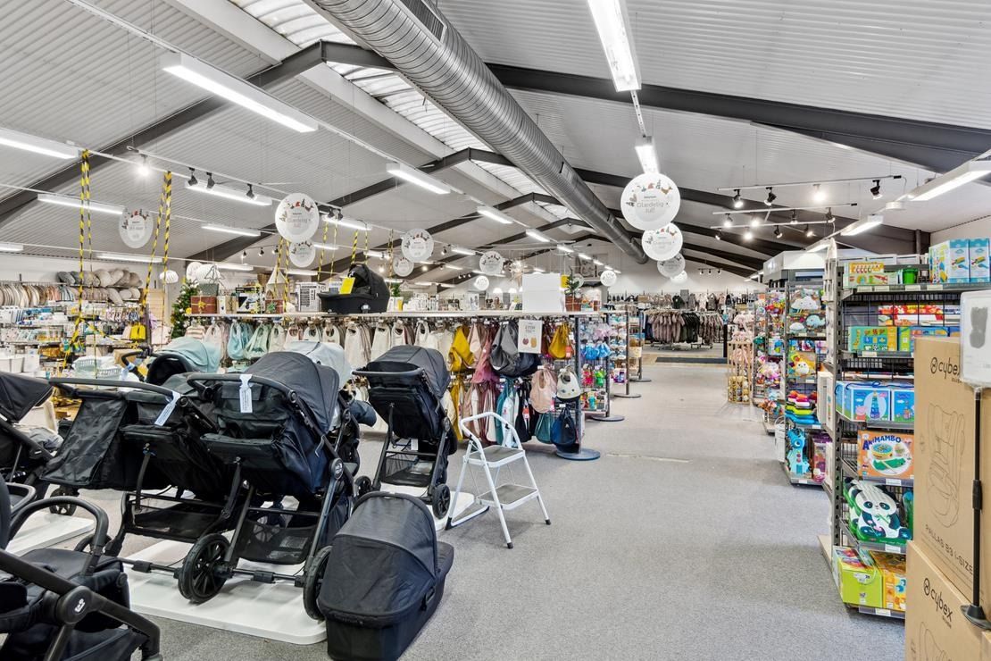 Foto af en babybutik med krybbe, sæde og udendørs produkter i en hvid, veludstyret bygning