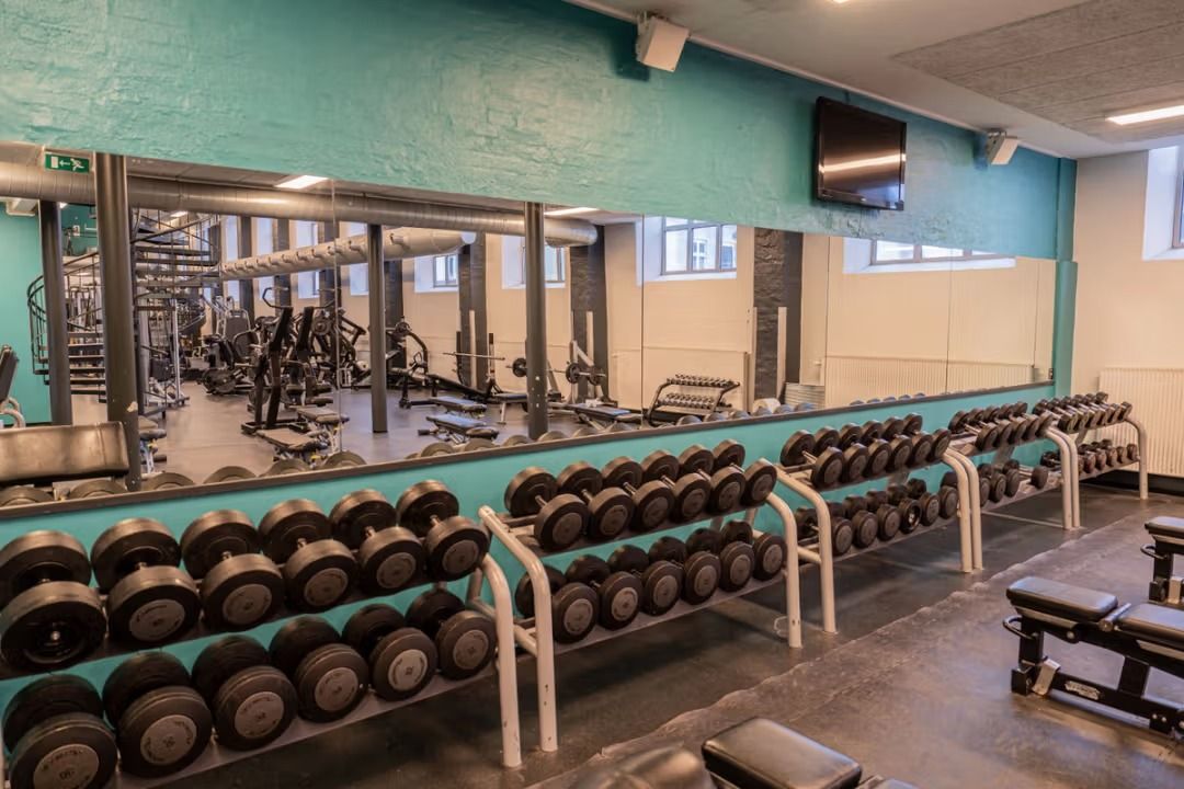 Fitnesscenter med stakket vægtsæt, styrketræning og udstyr samt fitnessapparater og spejle