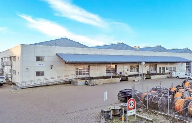 Et stort lager med en stor indkørsel og et stort antal røde kabelrulle på gaden