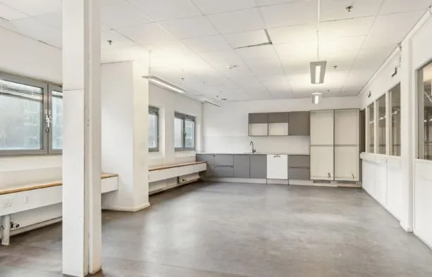 Lagerrum med hvide vægge, gulv og loft, vinduer og et køkken med hvide skabe og en vandhane