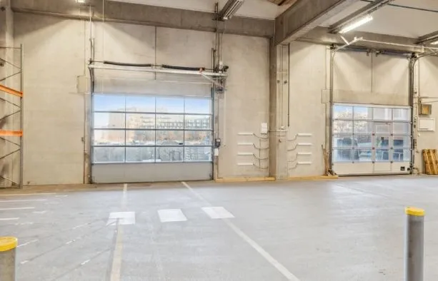 Lager med store garagedøre og vinduer med udsigt til bygninger udenfor og indre faciliteter