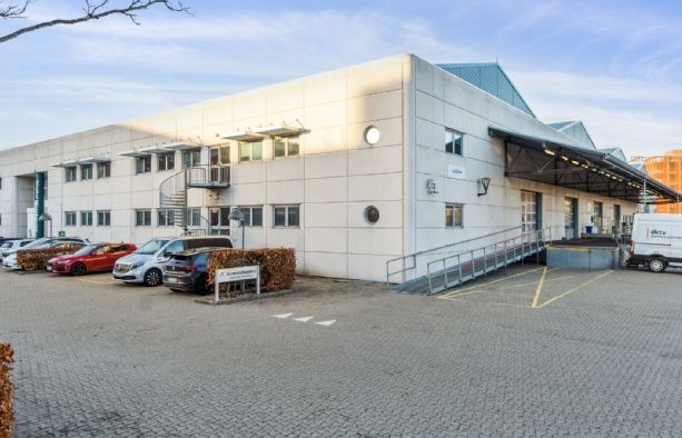 Lagerbygning med udsigt til parkeringsplads og flere biler parkeret udenfor bygningen
