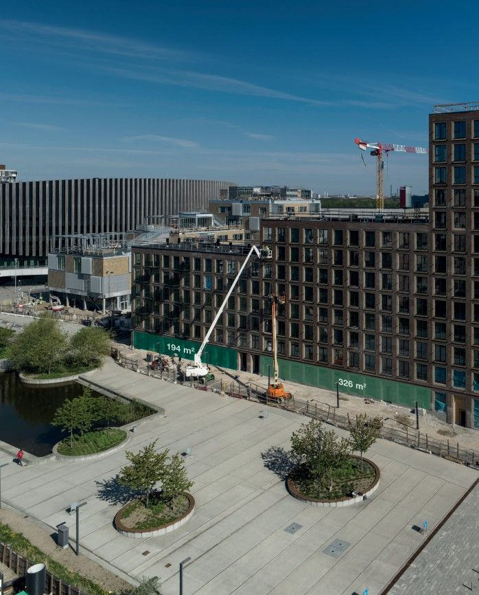 Et luftfoto af byggepladsen i Ørestad med flere højhuse og to krane, der ligger på byggepladsen