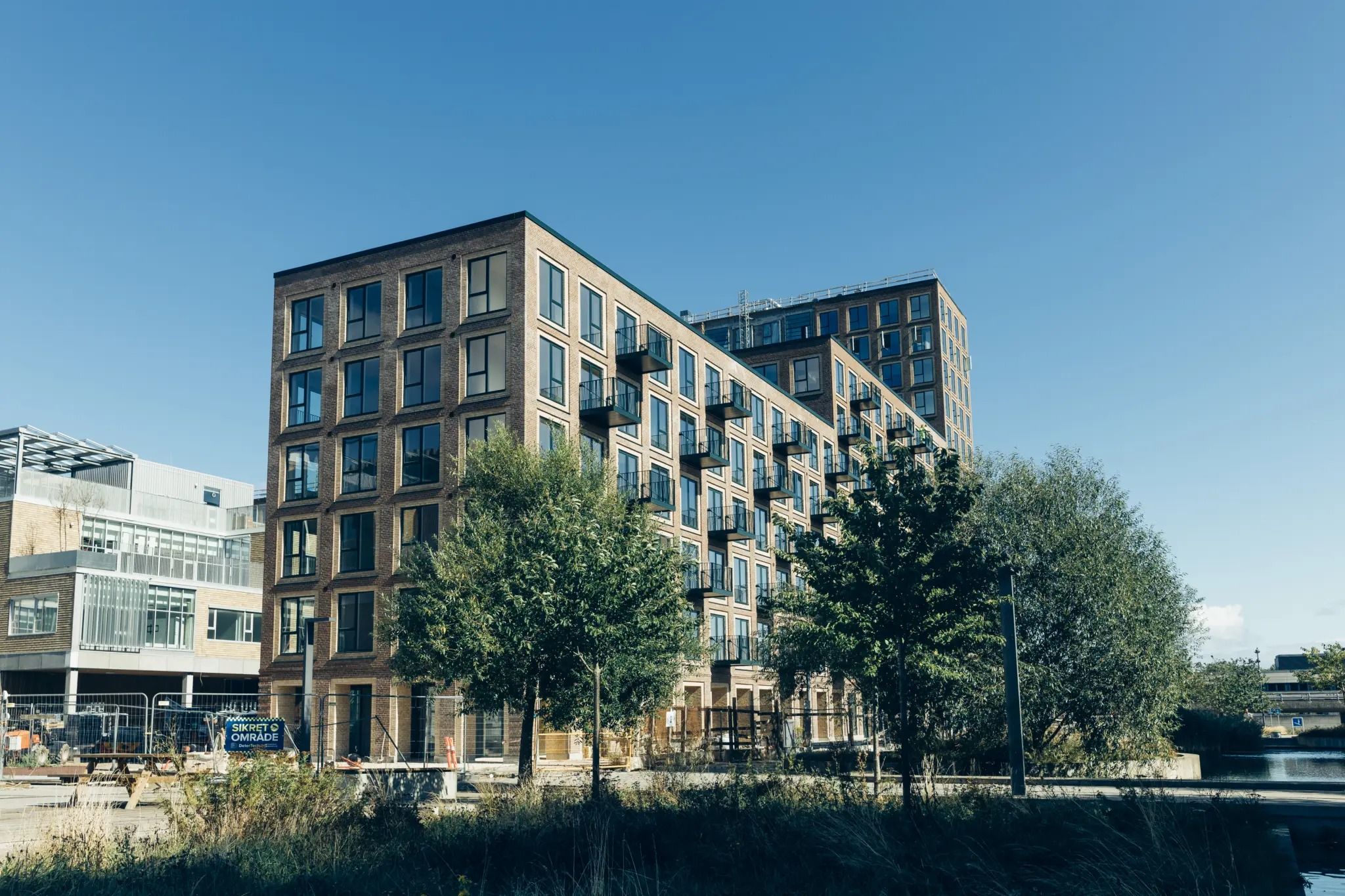Store lejlighedsbyggerier i Ørestad, der er under opførelse med udsigt over vandet og med planter og bollards foran