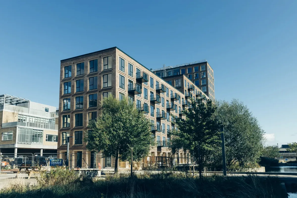 Store lejlighedsbyggerier i Ørestad, der er under opførelse med udsigt over vandet og med planter og bollards foran