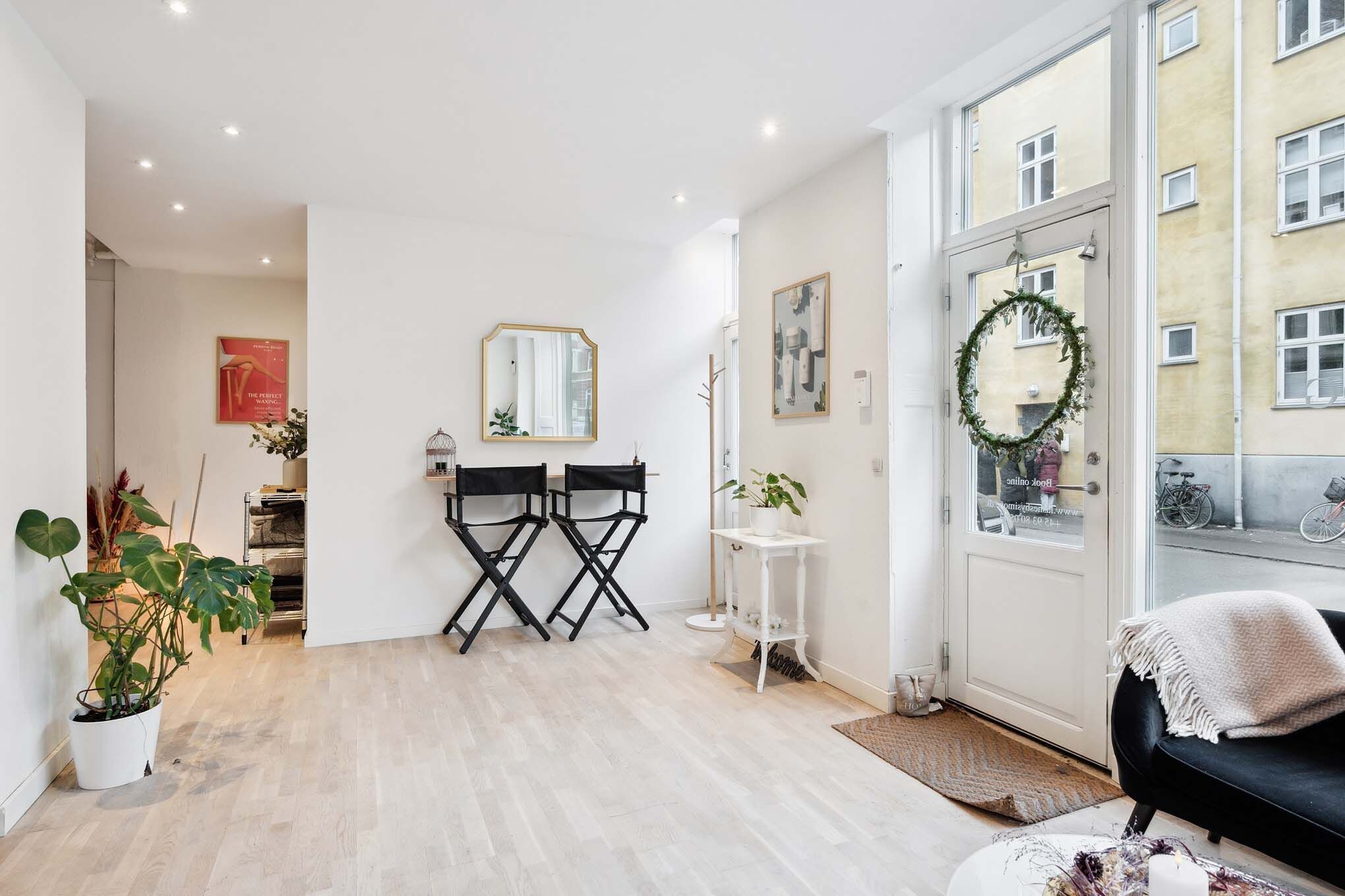 Nyrenoveret lokale til kosmetolog med to stole, spejl, blomster og et vægdekoration med plante i hvid vase