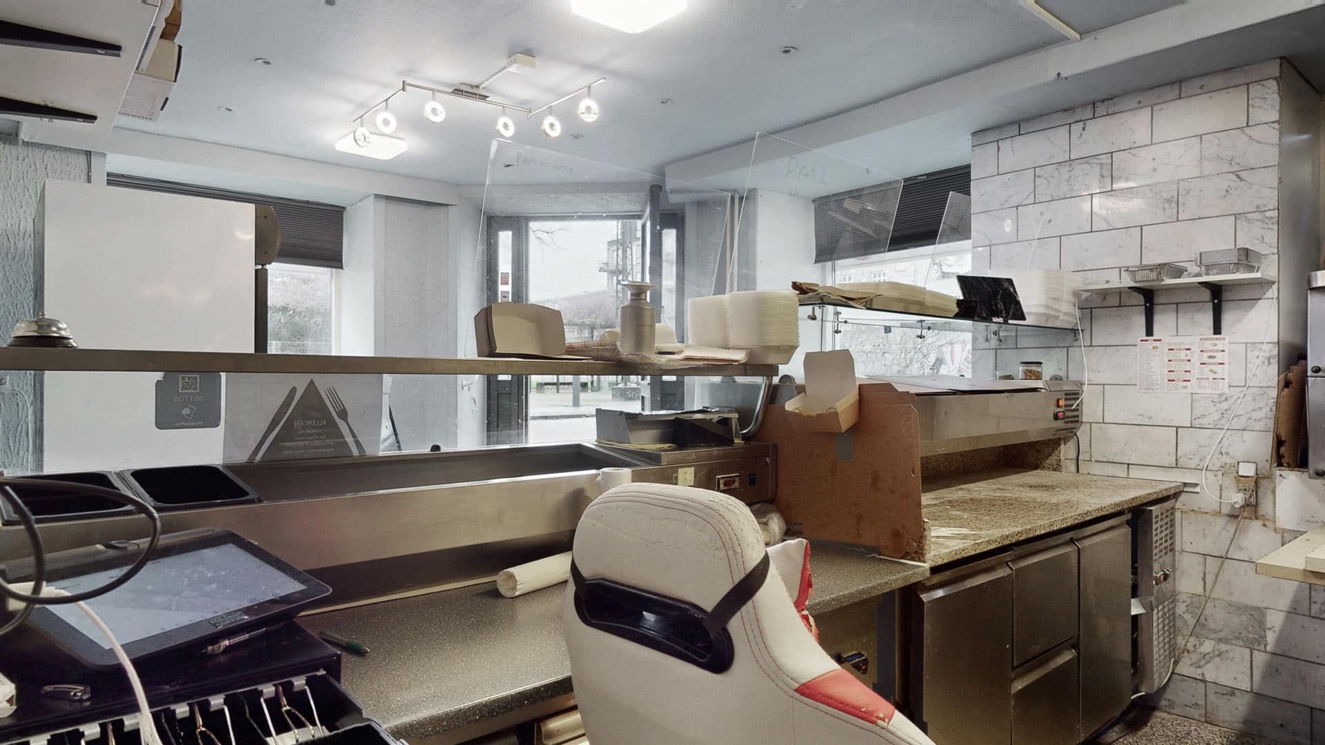 Erhvervslokaler med udstyr som kasser og hylder samt en stol med sikkerhedssele og en maskine med en stribe knapper og en