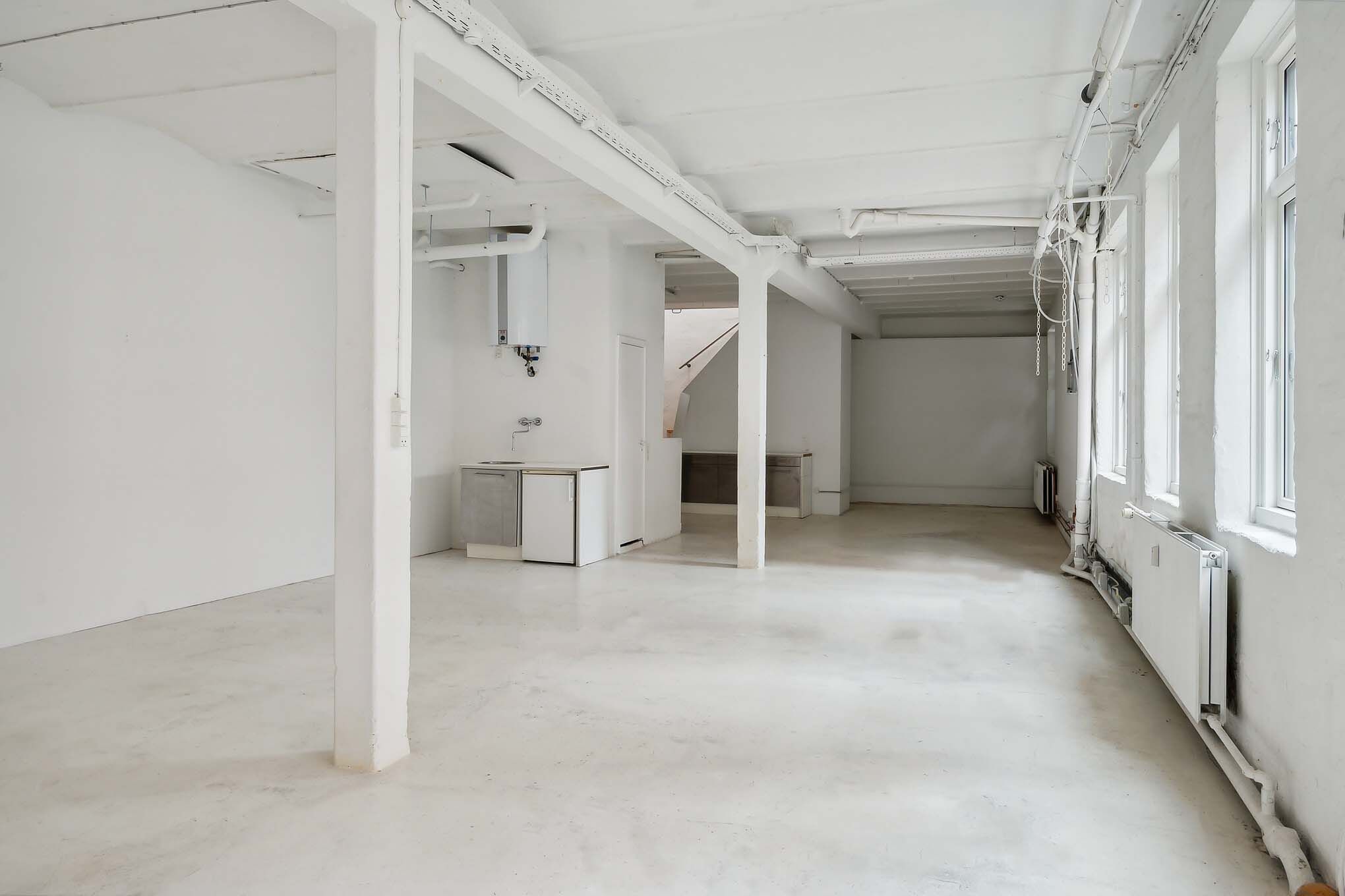 Lyst og højloftet rum med lyseruder og hvide vægge samt moderne interiørdesign, gulve og bjælker