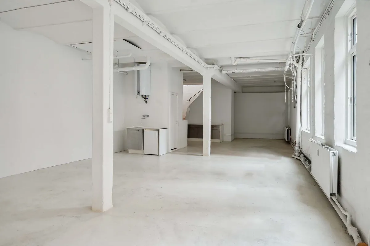 Lyst og højloftet rum med lyseruder og hvide vægge samt moderne interiørdesign, gulve og bjælker