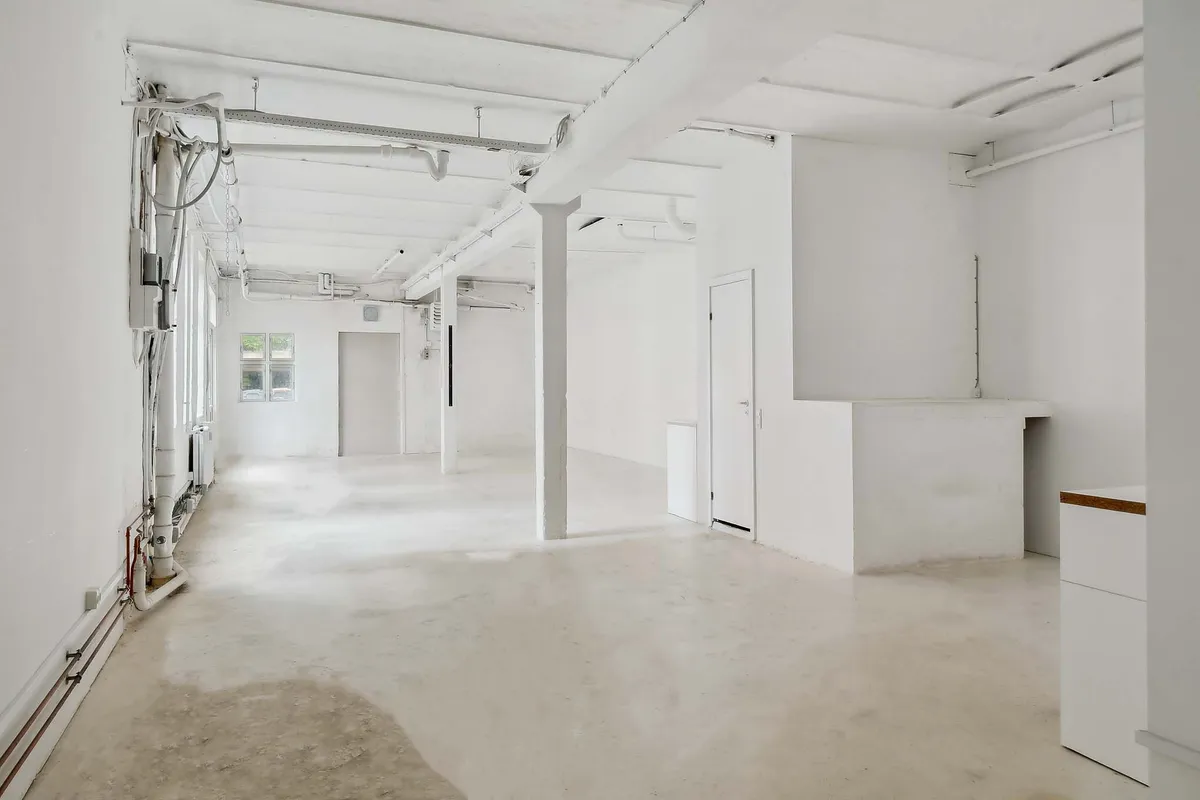 Ren, hvid og renset værksted med højloft og store vinduer på den ene side og høj loftsstrukturer på den anden side