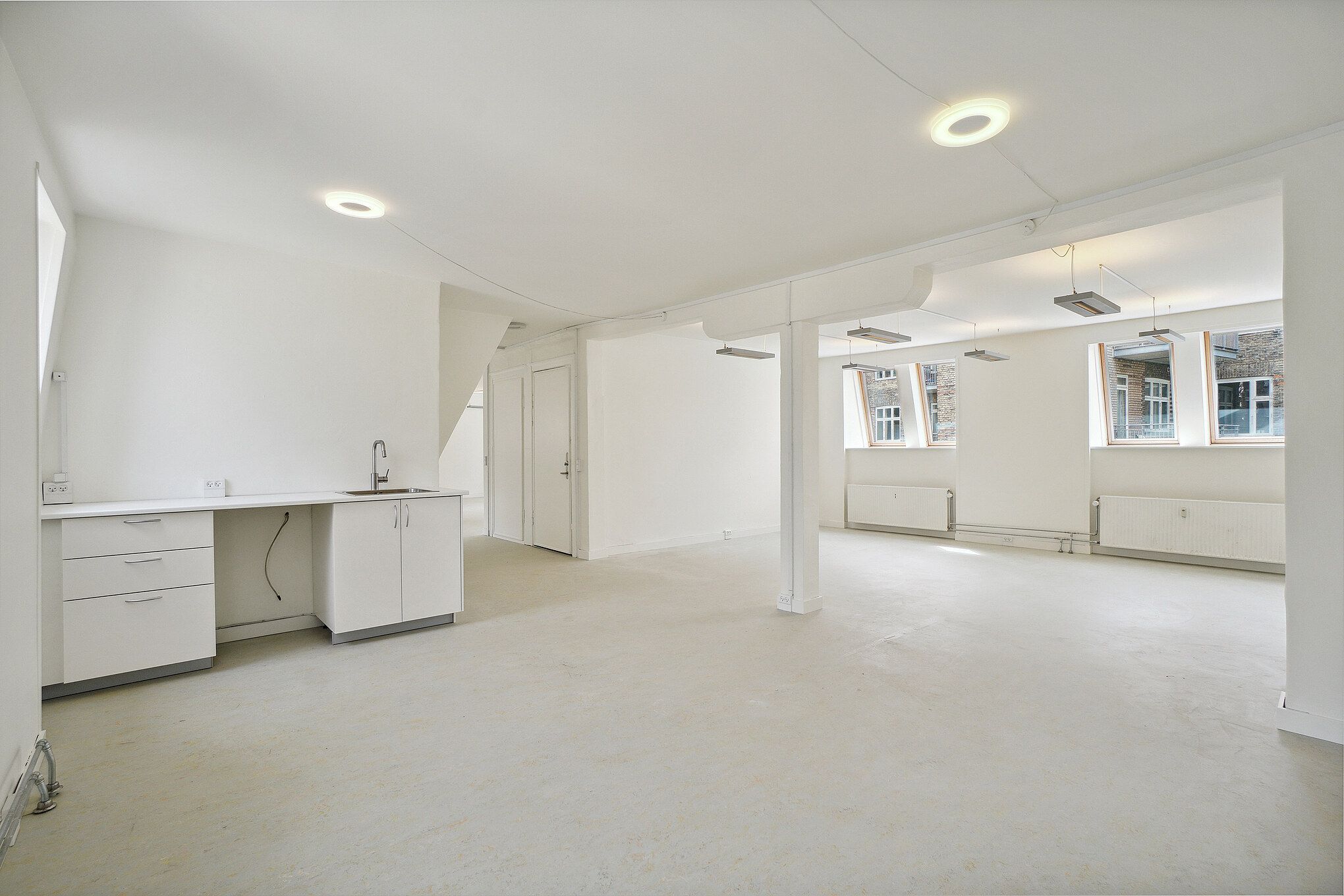 Lyst og moderne lejlighed med højloft og køkken med vask, radiatorer og vinduer i bagvæggen