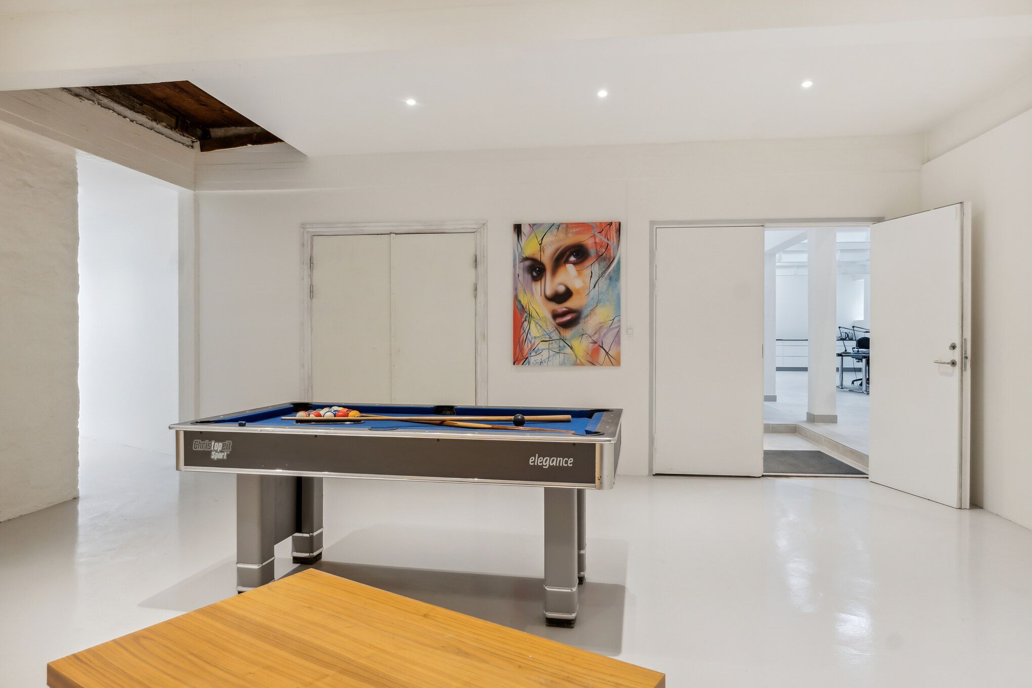 Lejlighed med luksuriøs indretning og elegant poolbord, moderne loftsværelse med åben dør og farverig maleri på væggen