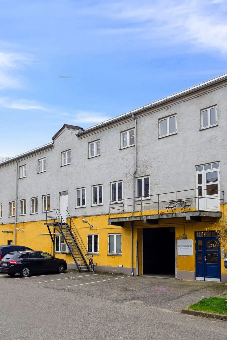 Lejemålet fremtræder i en sjælden stil med gule og grå vægge og mange vinduer, samt en parkeringsplads foran