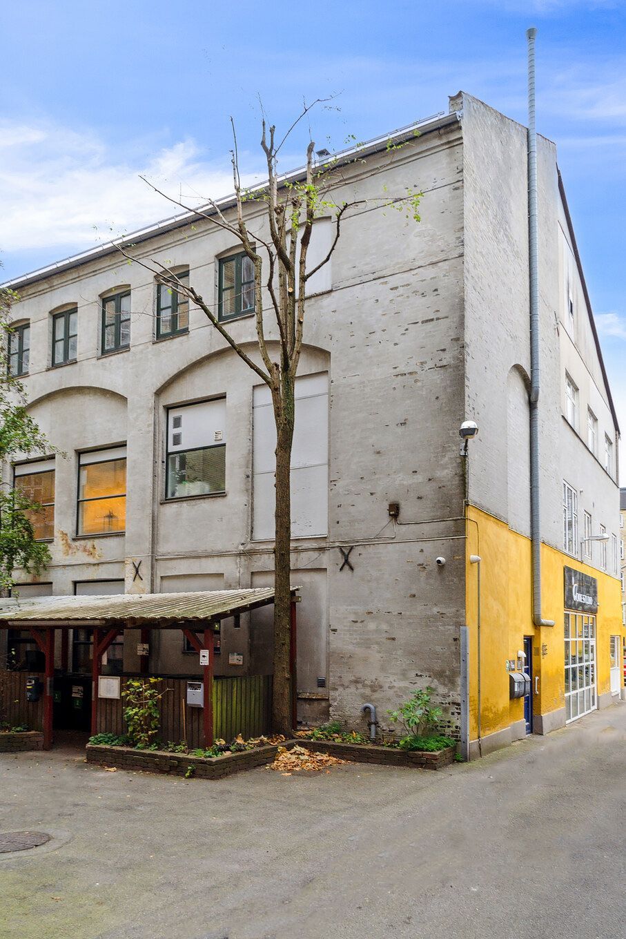 Lejlighed med loft til kip og stor vareelevator i et stort, lysegult og hvidt bygning med røde døre og glasruder, udstyret