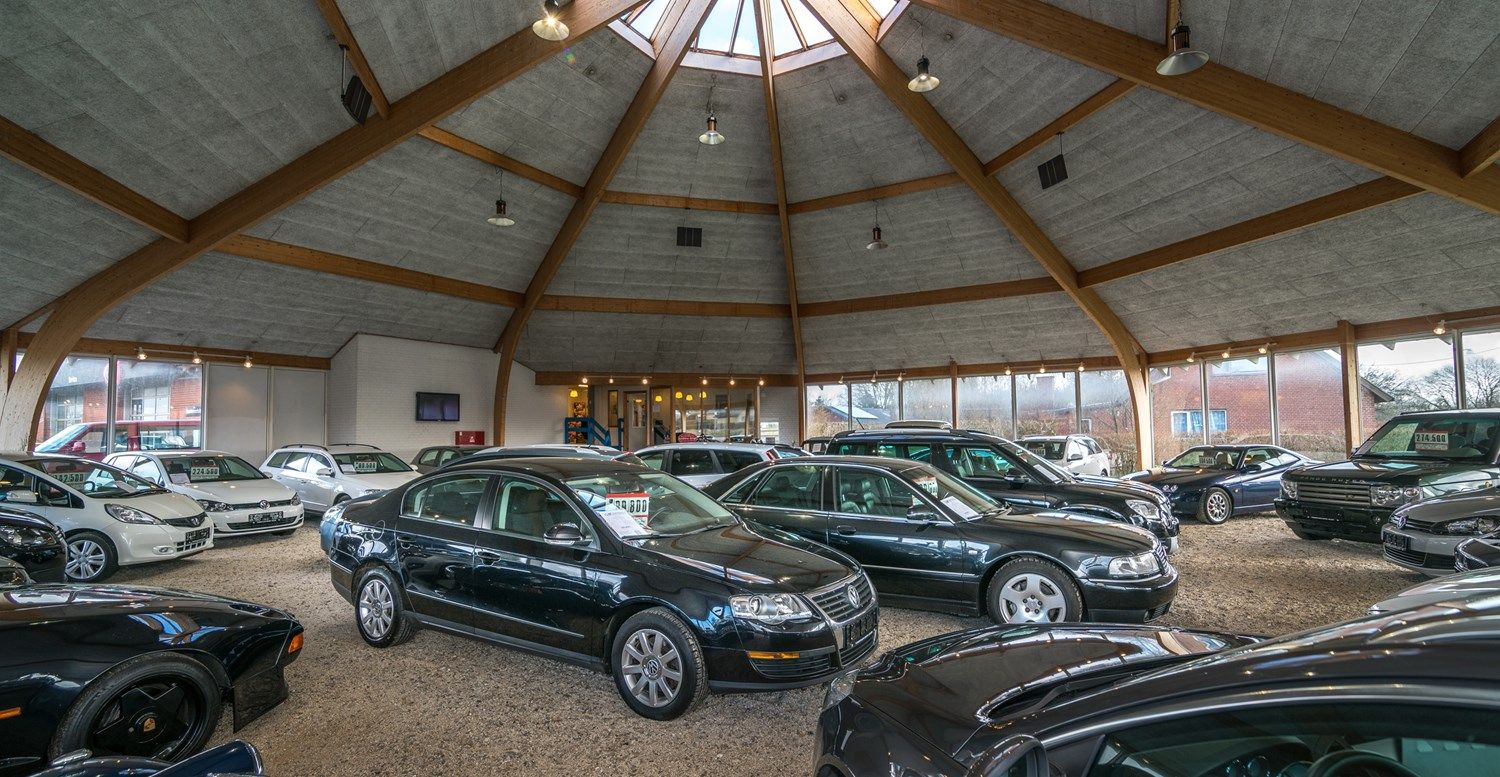 En stor bilforretning med flere biler, alle sorte og hvide, og mange biler parkeret i garagen