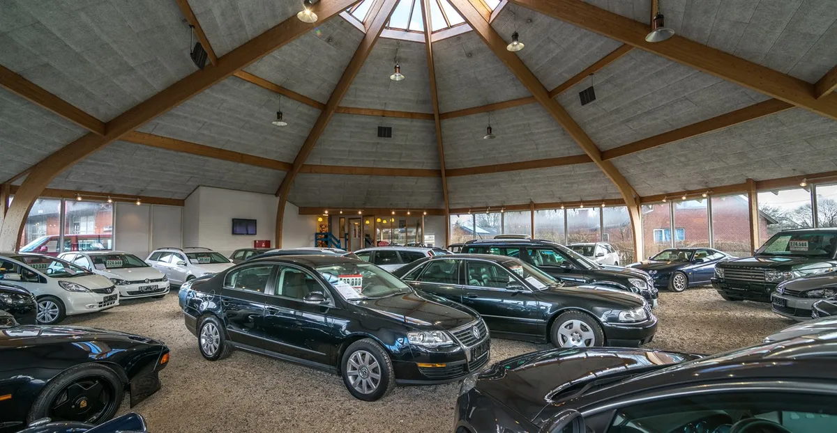 En stor bilforretning med flere biler, alle sorte og hvide, og mange biler parkeret i garagen