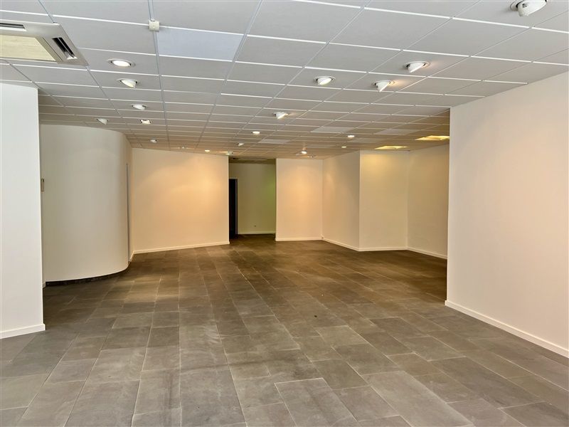 Rummeligt og velholdt detaillokale med højt til loftet, lysegulv og moderne lysekroner