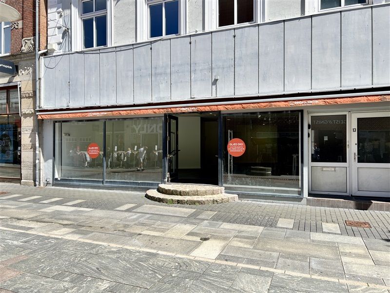 Detaillokale med glasdøre og udsalgsvindue med rødt forhæng og skrift på glasset