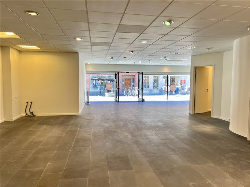 Rummelig detailforretning med store vinduer og glasdøre og indvendige gulvfliser