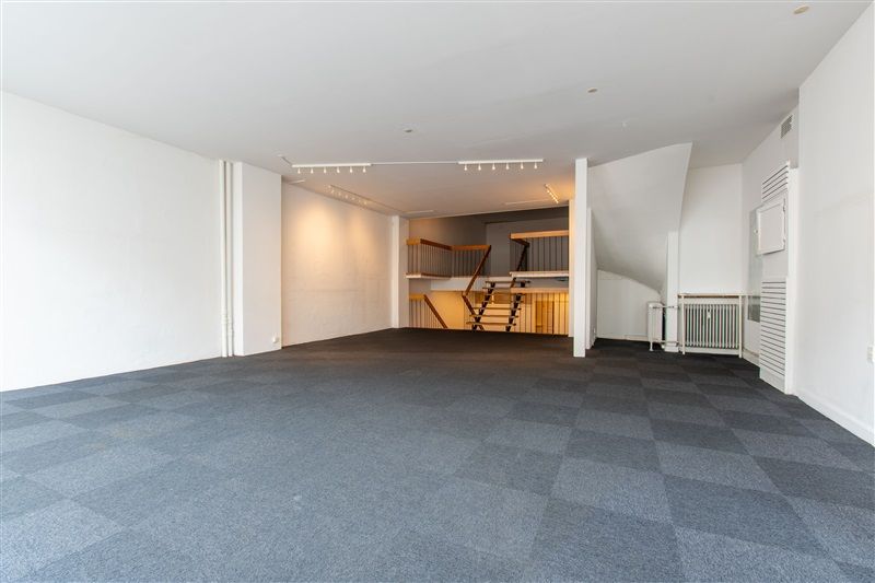 En tom kontorlokale med hvid malet væg og gulv samt loftsrum med trappe