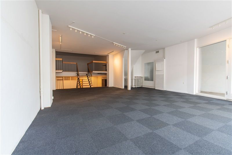 Store lokaler med lysegule vægge og grå karreleret gulv. Store glasvinduer og et højt loft med indbygget belysning. To