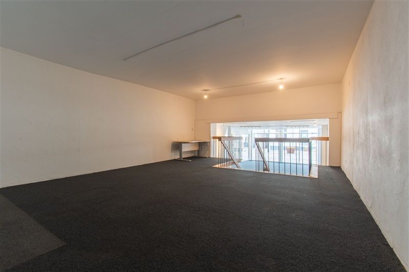Store lokaler med mørkegulv og hvide vægge, højt loft med lys, stort glasvindue og trappe op til første sal
