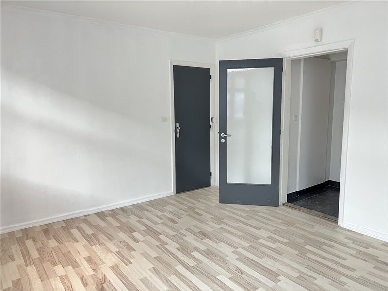 Lokale med lyse gulve, hvide vægge og tre døre i hvide og grå farver