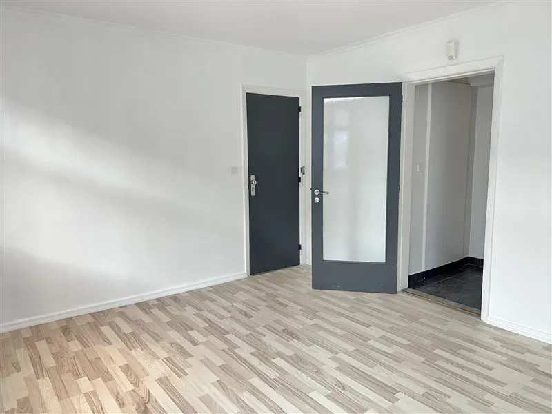 Lokale med lyse gulve, hvide vægge og tre døre i hvide og grå farver