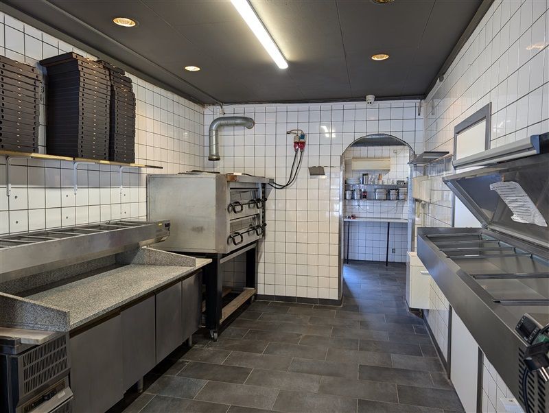 En moderne kommerciel køkken med rustfri stålapparater og apparater samt lysegrå og hvide mursten.