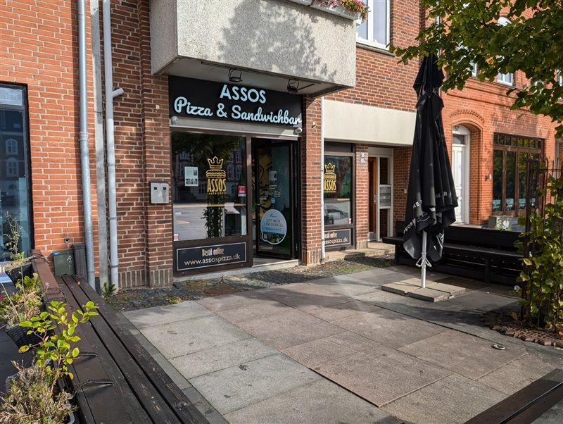 Pizza og sandwichrestaurant med udsigt til gaden, kælenavn Assos, med en stor sort paraply udenfor