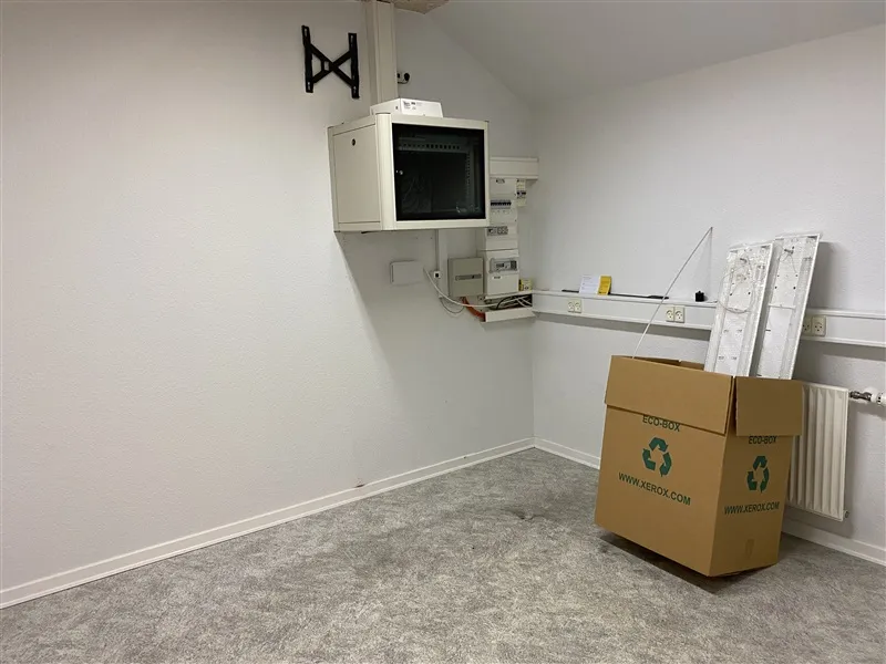 En hvid væg med et højt monteret mikroovn og en række elektriske installationer samt en afskærmet server.