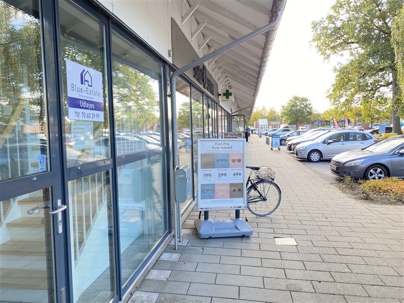 Glassdør og facade til Blue Estate Udlejes. Reklameskilt med priser på briller og reklame for fast pris hver maned. Cykel og